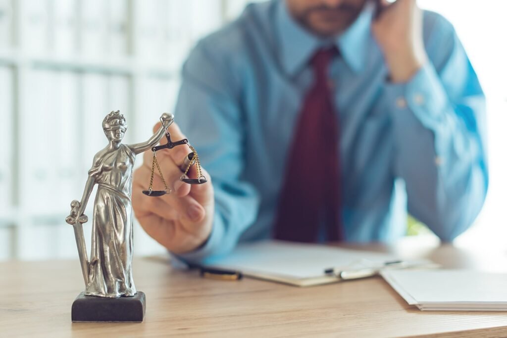 Persona preocupada frente a una estatua de la justicia